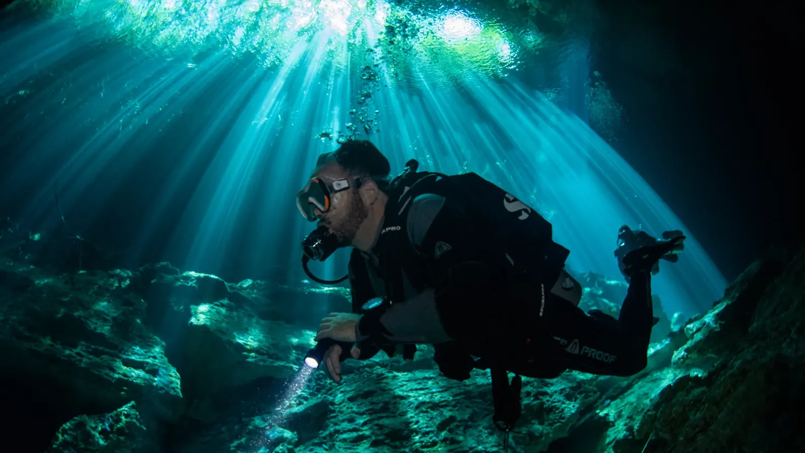 A scuba diver enjoying a close encounter with a giant manta ray while scuba diving in Cancun clear blue waters