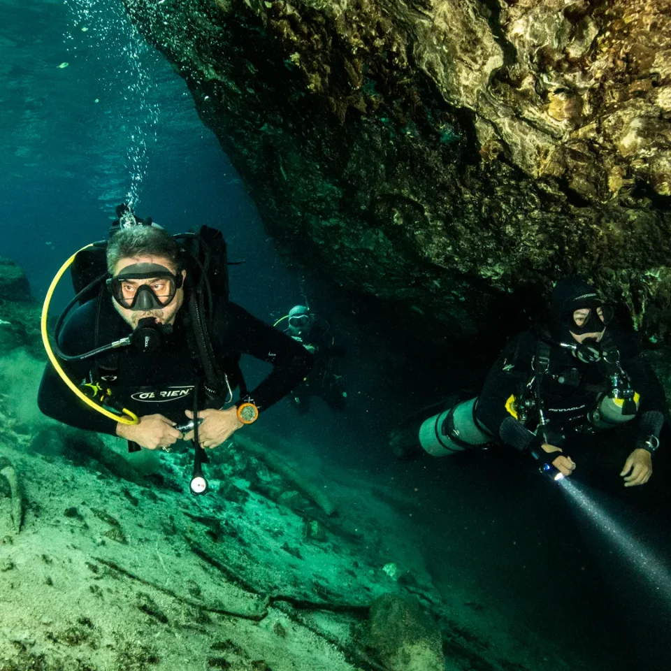 Two divers with torches at the cavern edge in Cenote Dream Gate