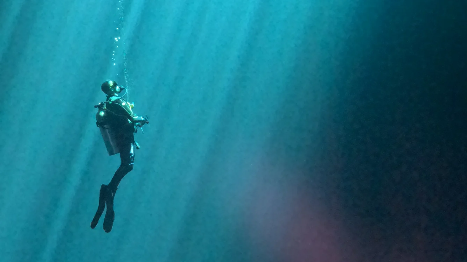 Diver ascending through the light of Cenote Maravilla
