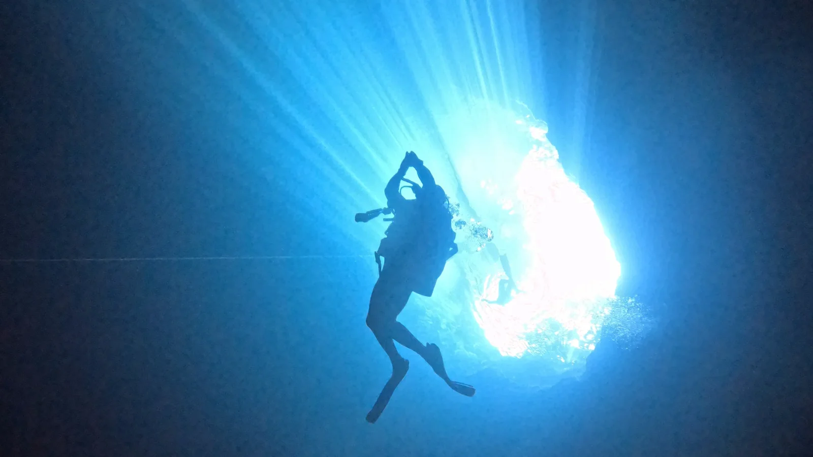 Diver silhouetted against the sunlit entrance of Cenote Maravilla