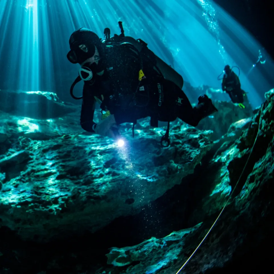 Divers under curtains of light in Cenote Ponderosa