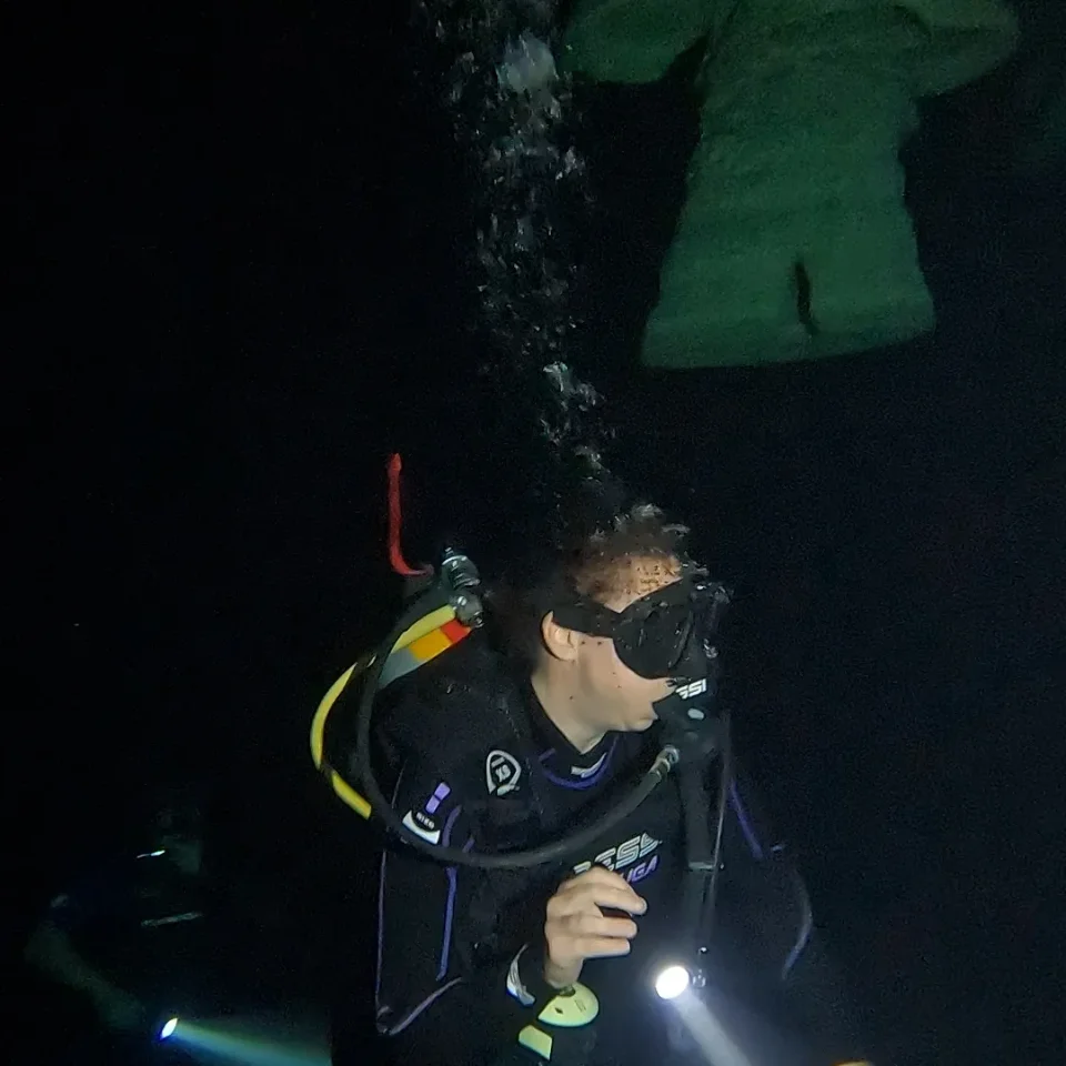 Diver with a torch in the dark chamber of Cenote Zapote