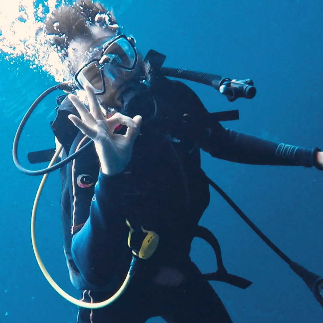 A scuba diver enjoying a close encounter with a giant manta ray while scuba diving in Cancun clear blue waters